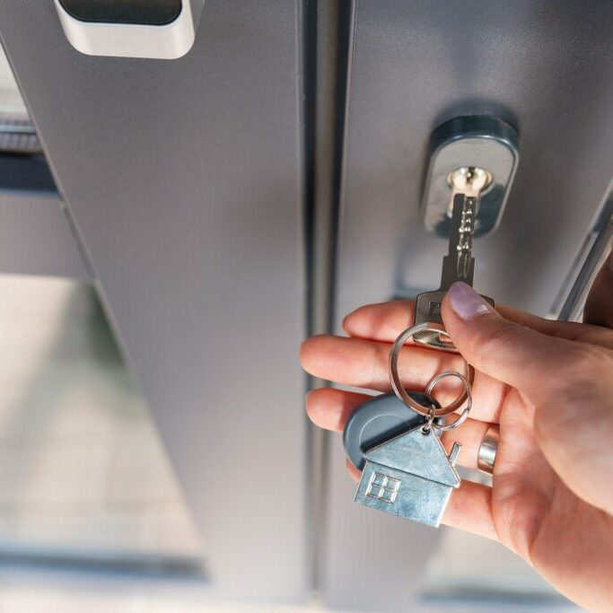 A woman's hand opens the door with a key on which the keychain hangs at home